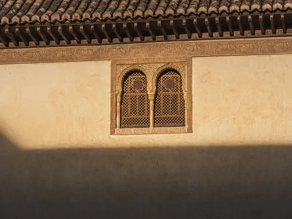 Duvara güneş ışığı ve Endülüs 'te ünlü bir Arap sarayı olan Alhambra' nın oymalı penceresi oymalı duvarlara ışık ve gölge saçıyor.