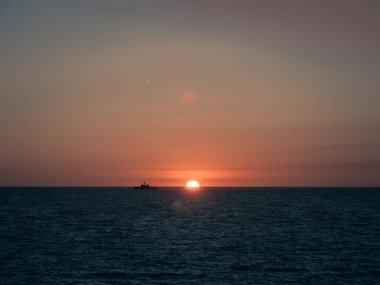 A military ship of the Spanish Navy sailing on the horizon during sunset, in Cadiz, Andalusia, Spain clipart