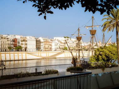 Nao Victoria taklit yük gemisi Guadalquivir Nehri 'ne yanaştı Seville, İspanya' nın Triana bölgesindeki evlerin önüne, gün batımının altın saatine.