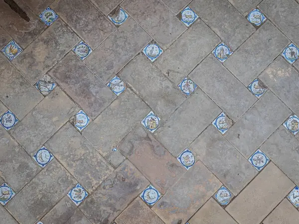 Medieval terracotta floor in Seville, Andalusia, with Spanish tiles picturing animals and houses, rustic vintage floor tiling garden