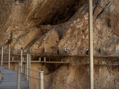 El Chorro, İspanya, 15 Eylül 2023: Endülüs, Malaga, İspanya 'daki El Caminito del Rey vadisindeki eski harabe vadisinin üzerinde yürüyen bir grup turist