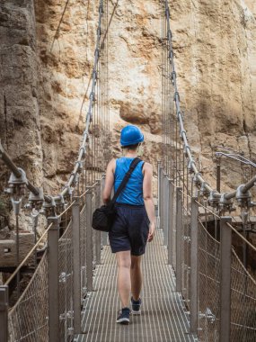 İspanya 'nın Endülüs kentindeki Guadalhorce nehrinin kanyonundaki El Caminito del Rey yolunda yürüyen genç bir bayan turist.