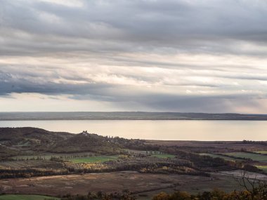 Macaristan 'ın Balatonfelvidek bölgesindeki Szigliget Dağı ve Balaton Gölü' nün panoramik manzarası. Balaton 'un ön planında sonbahar, günbatımına yakın şarap bölgesi, pembe renkler.