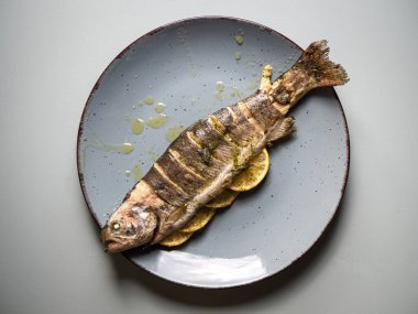 Limon dilimleriyle doldurulmuş bir tabakta kızartılmış somon balığı. Ödünç vermek için balık yemi.