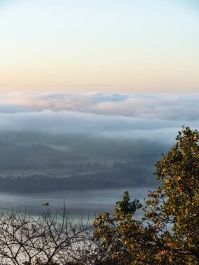 Macaristan 'da sonbahar gündoğumu boyunca tarım arazileri, yollar ve ormanlar üzerindeki yoğun sis bulutu, güzel renkler, karamsar manzara