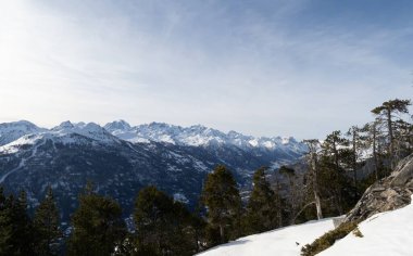 Fransız Alplerindeki Serre Chevalier Briancon kayak merkezinin panoramik görüntüsü. Karla kaplı tepeler, yemyeşil ağaçlar ve açık bir gökyüzü kayak ve açık hava maceraları için mükemmel bir kış manzarası yaratır..