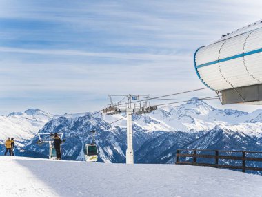 Briancon, Fransa, 29 Ocak 2024: Serre Chevalier, Briancon, Fransa 'da bir teleferik istasyonu yakınlarındaki kayakçıların karla kaplı dağların manzarası. Açık mavi gökyüzü ve kış
