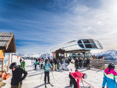 Briancon, Fransa, 29 Ocak 2024: Serre Chevalier, Briancon, Fransa 'da bir teleferik istasyonu yakınlarındaki kayakçıların karla kaplı dağların manzarası. Açık mavi gökyüzü ve kış
