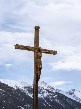 İsa 'yı tasvir eden taşralı ahşap bir haç, karla kaplı dağların çarpıcı zeminine kurulmuş ve Briancon yakınlarındaki Fransız Alplerinde sakin bir gökyüzü.