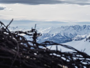 Rusted barbed wire near WW2 fortifications on Mont Chaberton, France, with snow-covered peaks and a dramatic cloudy sky. Highlights history amid rugged alpine scenery. clipart