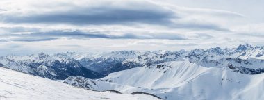 Mont Chaberton, Fransa 'dan gelen karlı Alpler' in panoramik görüntüsü. Engebeli tepeler üzerinde dramatik bulutlar uzanıyor, dingin ve evcilleşmemiş dağ manzarasını gözler önüne seriyor..