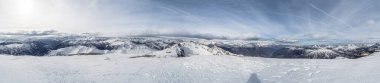 A breathtaking panoramic view of Mont Chaberton's snow-covered peaks, expansive alpine landscape, and bright skies with wispy clouds and contrails. clipart