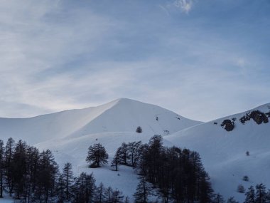 A serene view of snowy mountain peaks in the French Alps, with trees scattered on the slopes. Nearby towns include Chamonix, Annecy, and Grenoble. clipart