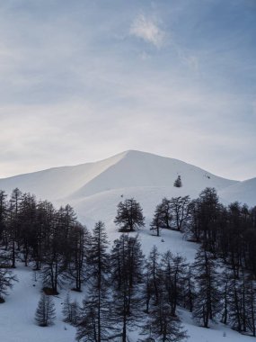 Fransız Alpleri 'ndeki karlı dağ zirveleri, yamaçlara dağılmış ağaçlar. Yakın kasabalar arasında Chamonix, Annecy ve Grenoble yer almaktadır..