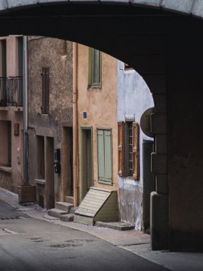 Briancon, Fransa 'da dar bir sokak, tarihi binalarla dolu ve gölgeli bir kemer yolu ile çerçevelenmiş. Yumuşak güneş ışığı, eski taş ve pastel cephelerin dokusunu ön plana çıkarıyor..