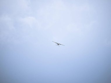 Küçük bir uçak engin, bulutlu bir gökyüzünde süzülür, açık havada izole bir şekilde görünür. Minimalist kompozisyon gökyüzünün enginliğini vurgular..