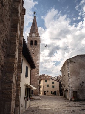 Basilica di Sant Eufemia 'nın ikonik çan kulesi İtalya' nın Grado kentindeki sakin taşlı bir meydanın üzerinde yükselir. Uçan bir kuş ve yumuşak bir ışık büyüyü artırır.