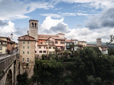The historic Devil's Bridge crossing the Natisone River with pastel old town buildings in Cividale del Friuli, Italy.