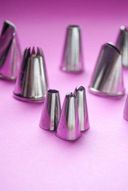 Baking tools, variety of piping tips on a pink background clipart