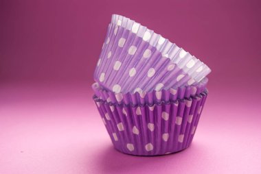 Renkli puantiyeli kek kaplarının, fırın aksesuarlarının, pembe arka planda.