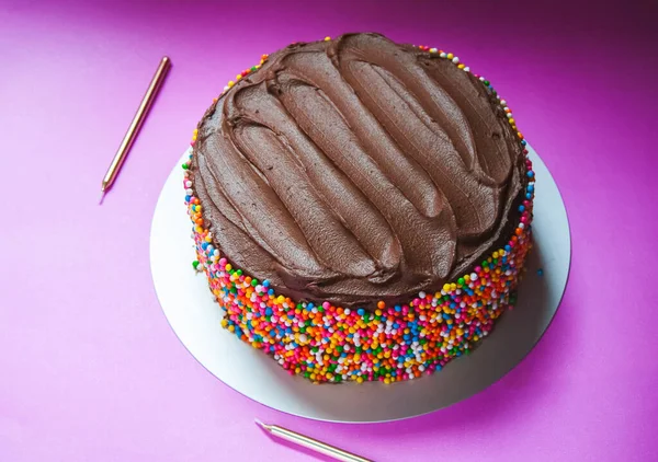 stock image Delicious chocolate ganache birthday cake with colorful sprinkles on a pink background