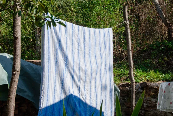 Vintage blue stripes duvet cover drying in the sun, rustic clothes line, rural, village life