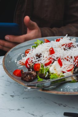 Masadaki beyaz tabakta peynirli ve sebzeli salata.