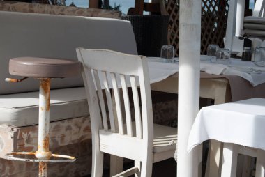 Rustic Mediterranean Outdoor Restaurant Seating with White Chairs and Tablecloths