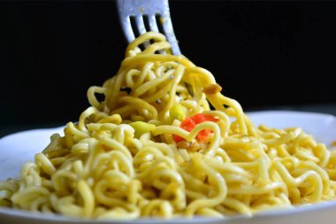 Siyah arka planda çatalı olan lezzetli bir makarna.