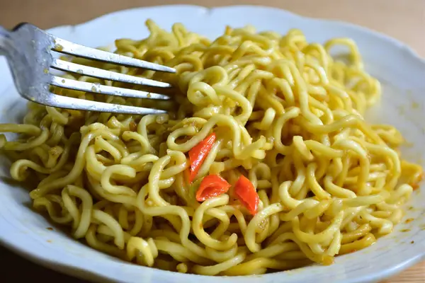 Çatalla beyaz bir kasede hazır erişte.