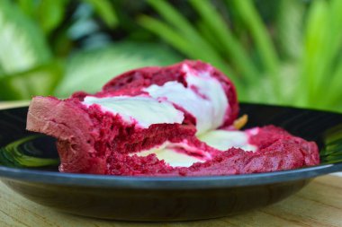 Siyah bir tabakta cam bir bardakta bir parça dondurma..