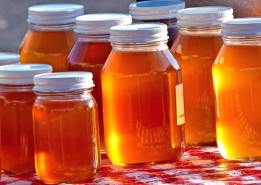 Sabah güneşi altında parlayan bal, 66. yoldaki Sapulpa Çiftçi Pazarı 'nda kırmızı beyaz bir elbisenin üzerinde duruyor..