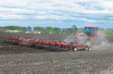 Bir tarım traktörü, bir bahar günü, ekiciyle toprağı işliyor. Toprağı ekime hazırlıyorum..