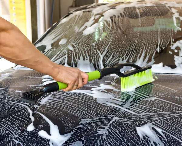 stock image The car undergoes a thorough cleaning with high pressure water in an open car wash.