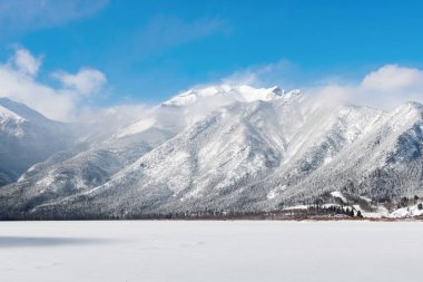 Kanada Kayalık Ulusal Parkı kışın. Alberta, Kanada. Orman ve karlı dağlar. Mavi gökyüzü ve beyaz bulutlar arka planda.