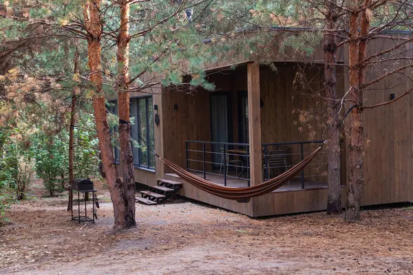 Huzurlu bir orman ortamında, hamak ve açık hava mobilyalarıyla yerleştirilmiş ahşap kulübe inzivası, doğal sakinlik ve kırsal cazibe gösterisi, rahatlama, kamp deneyimleri ve doğa ile bağlantı için ideal..