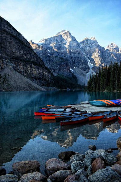 Moraine lake with canoes and mountains in background.