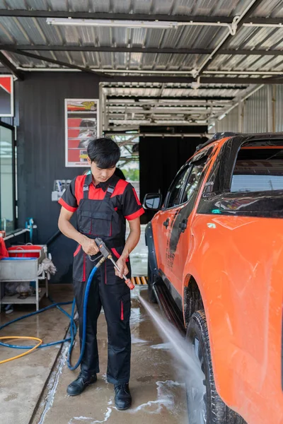 Asyalı Erkek Işçi Onları Temizlemek Için Araba Tekerleklerine Püskürtüyor — Stok fotoğraf