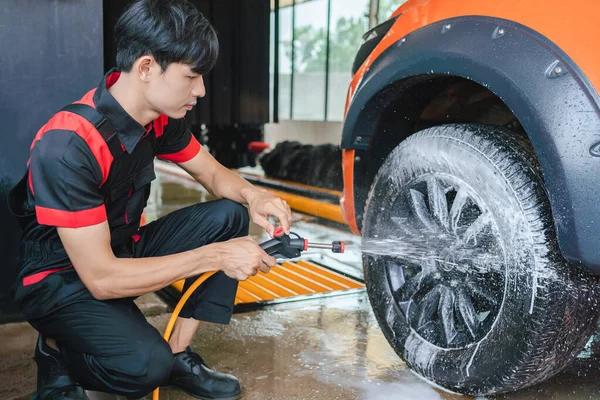 Asyalı Erkek Işçi Araba Tekerleklerine Köpük Püskürterek Temizliyor — Stok fotoğraf