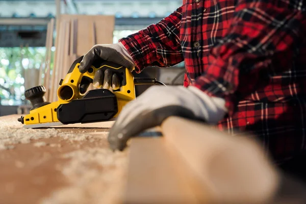 Stock image hand holding planing tools A side view of a carpenter wearing a plaid shirt. homework carpenter