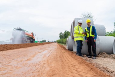 Asyalı mühendis ve müteahhit tablet aracılığıyla bilgi bularak inşaat alanında planlama yapıyorlar