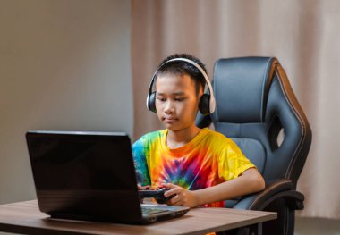 Asyalı çocuk boş zamanlarında evde online olarak rekabetçi oyunlar oynuyor. joystickle