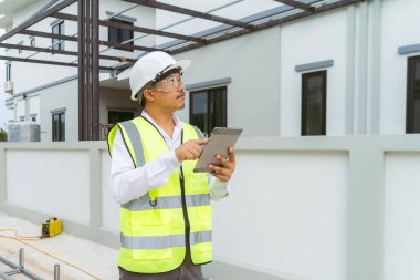 Bir ev mühendisi köyün projesini tabletle kontrol eder ve fotoğrafını çeker..