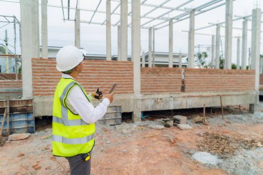 Evin yapısını inceleyen mühendis elinde telsizle içeride duruyor.