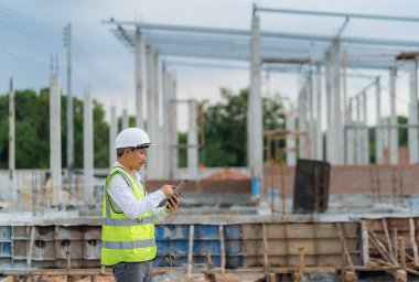 Ev yapımı projesinde cep telefonları, tabletler ve modern teknoloji ile yapı denetleme mühendisi.