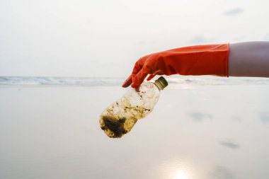 Plajda plastik toplayan kadın elleri plaj gönüllüleri, sahil ve su kirliliği kavramının plastik şişelerini topluyor. Çevre koruma günü kavramı