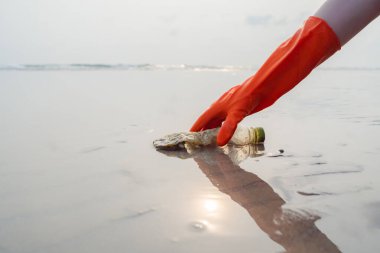 Plajda plastik toplayan kadın elleri plaj gönüllüleri, sahil ve su kirliliği kavramının plastik şişelerini topluyor. Çevre koruma günü kavramı