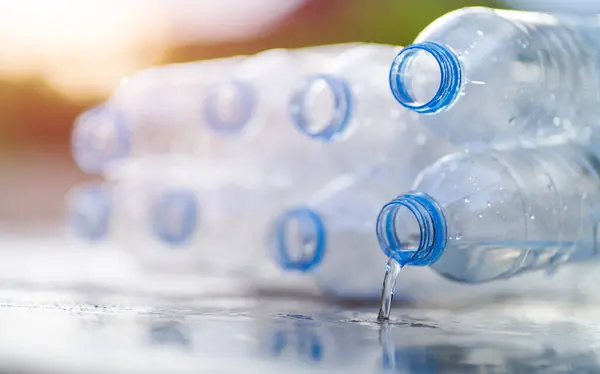 Water Flowing Plastic Drinking Bottles Concrete Floor — стоковое фото