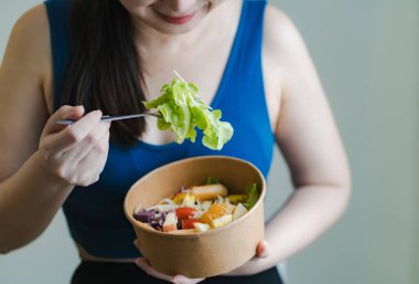 Alternatif gıda, meyve ve sebze salatası yiyen spor elbiseli kadın, kilo kontrolü ve sağlık için diyet konsepti.