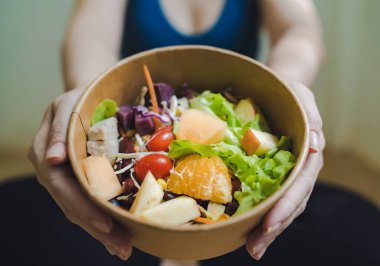 Mavi spor elbiseli kadın elinde sebze, salata ve meyve tabağı tutuyordu. Alternatif gıda konsepti ve kilo kontrolü için diyet..